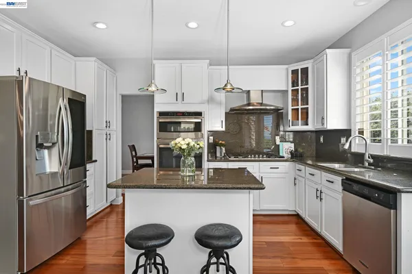 a kitchen with stainless steel appliances granite countertop a refrigerator a sink dishwasher a stove and a refrigerator