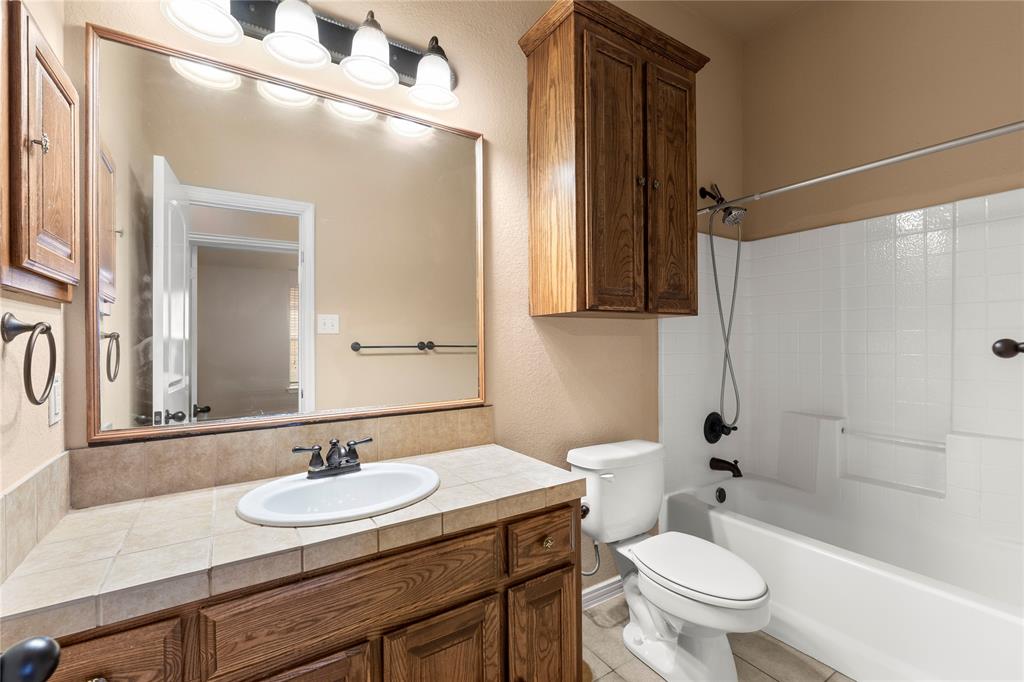 8245 Edgepoint Trail Fort Worth, TX 76053 - Photo 11 of 28 a bathroom with a granite countertop sink toilet a mirror and shower