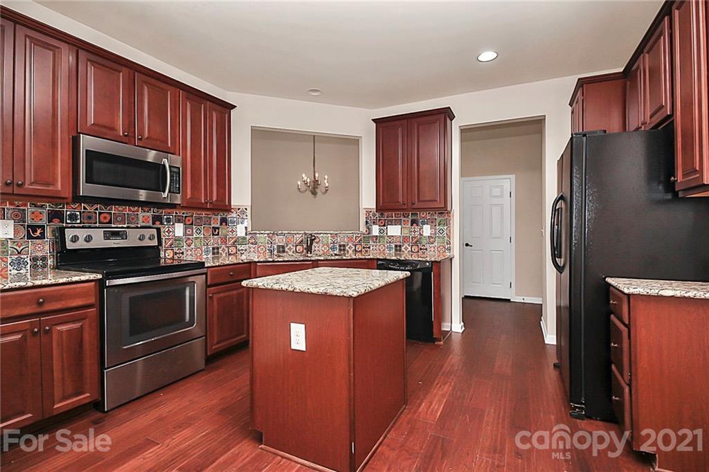 109 Inlet Point Drive Tega Cay, SC 29708 - Photo 5 of 48 a kitchen with stainless steel appliances granite countertop a stove a sink dishwasher a refrigerator and a microwave oven with wooden floor