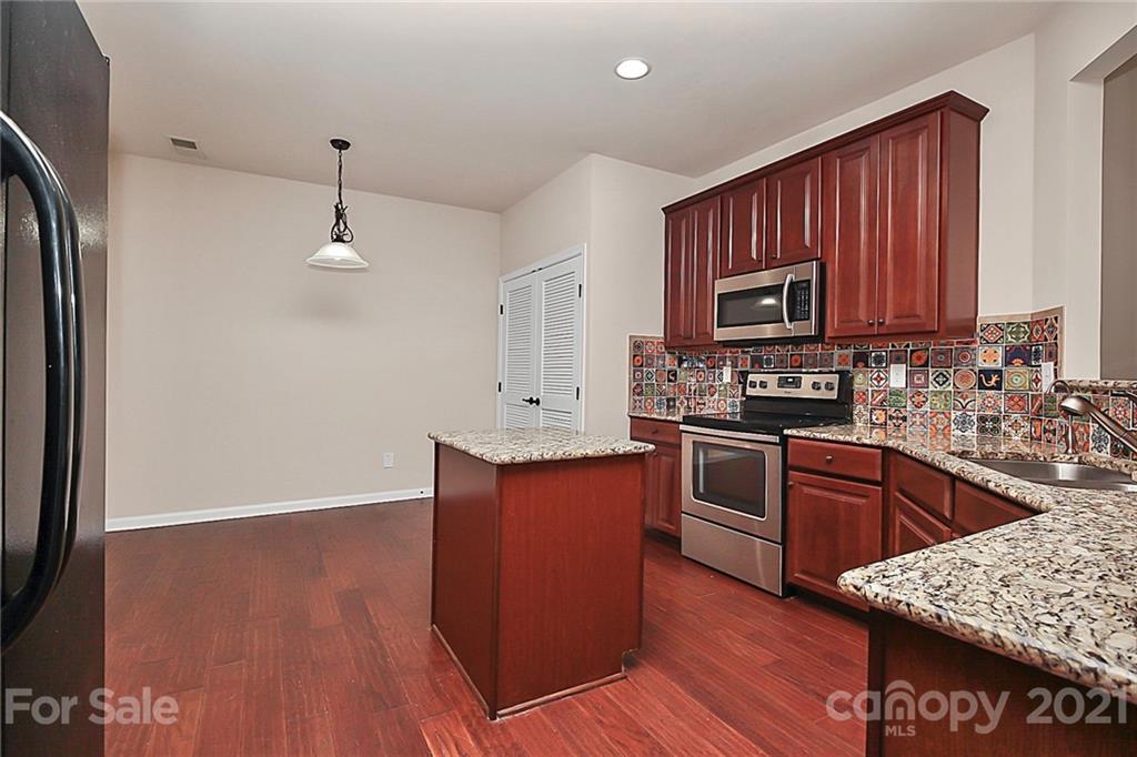 109 Inlet Point Drive Tega Cay, SC 29708 - Photo 7 of 48 a kitchen with granite countertop wooden floors a stove and a microwave