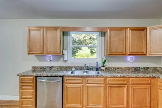 a kitchen with granite countertop white cabinets sink and window