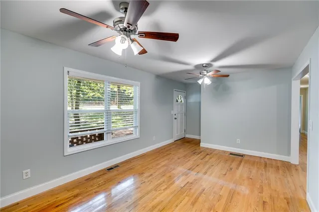 a view of an empty room with wooden floor and a window