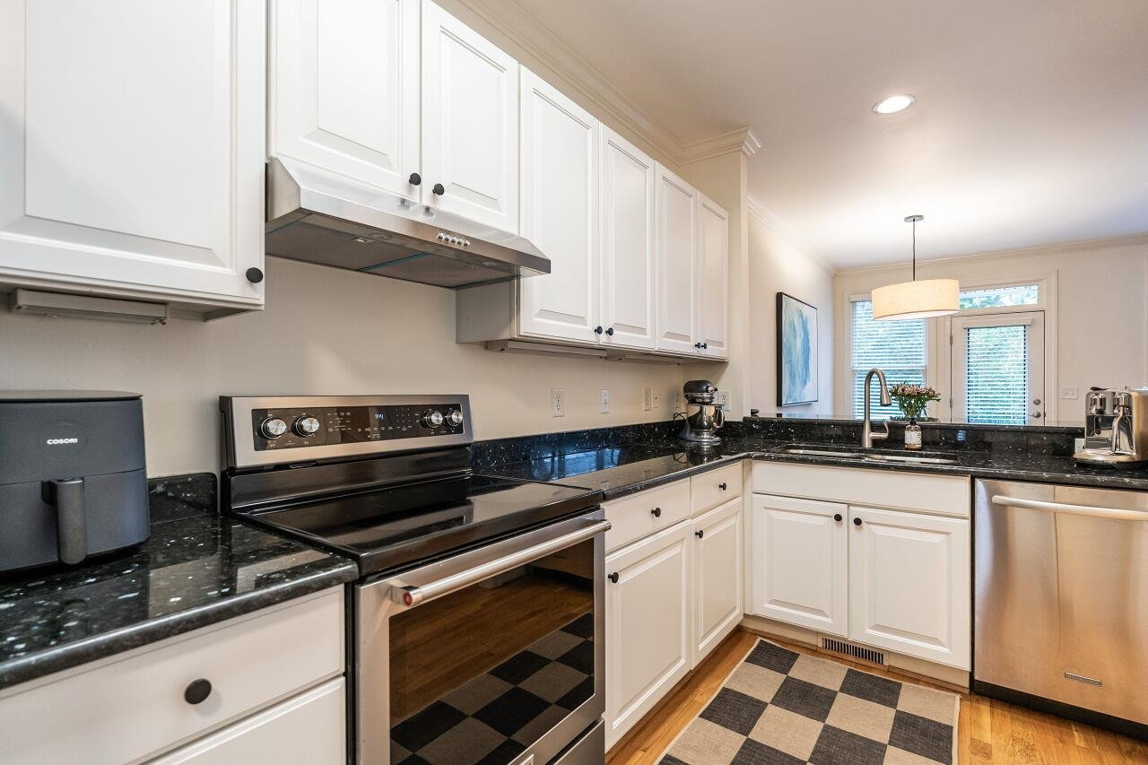 Kitchen with white cabinets, granite tops, Kitchen Aid Range/Oven, KA Dishwasher, SS Refrigerator and hardwood floors. Kitchen
