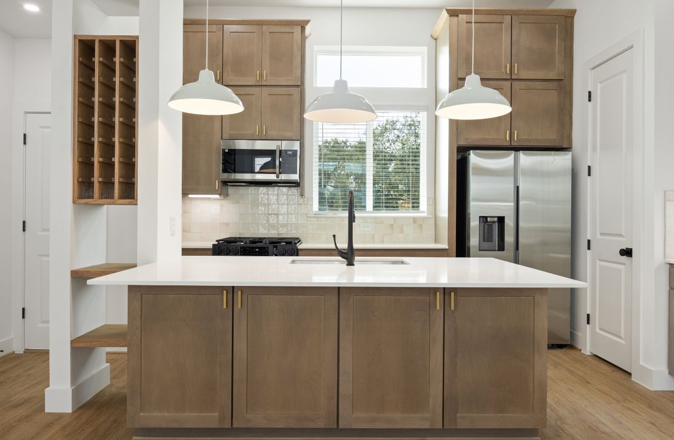 2121 Hoskins Drive, Unit C Houston, TX 77080 - Photo 18 of 34 The kitchen centers around a large quartz island with pendant lighting, warm wood cabinetry, brass-toned hardware, black faucet, stainless steel appliances, gas cooking, and a built-in wine/display feature. Tall cabinets and a bright window add style, storage, and natural light to this chef-inspired space.