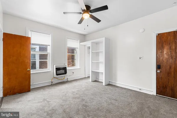 a view of a livingroom with furniture a ceiling fan and windows