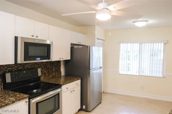 a kitchen with granite countertop a refrigerator stove and microwave