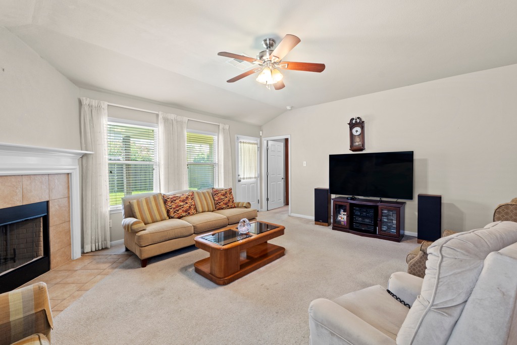 12008 Lansdowne Road Austin, TX 78754 - Photo 8 of 29 Step into a sun-filled living area featuring a cozy fireplace and vaulted ceilings.
