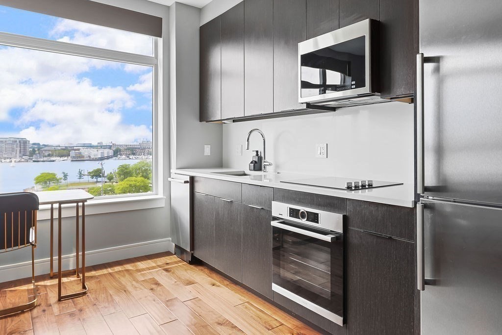 99 Sumner Street, Unit 623 Boston, MA 02128 - Photo 4 of 15 a kitchen with kitchen island granite countertop a refrigerator stove and microwave