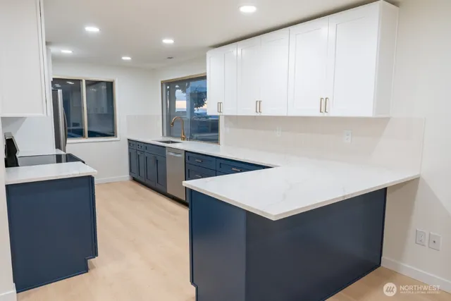 a large kitchen with stainless steel appliances a sink dishwasher stove top oven and cabinets