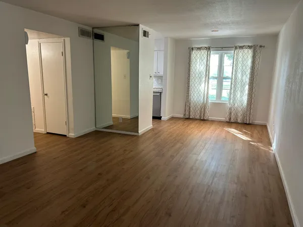 an empty room with wooden floor and windows