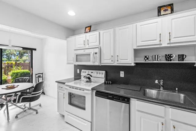a kitchen with stainless steel appliances a white stove top oven and white cabinets