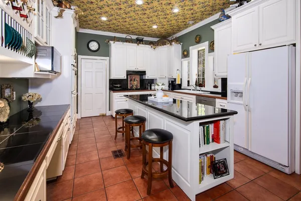 a kitchen with stainless steel appliances a stove a refrigerator a sink a stove and white cabinets with wooden floor