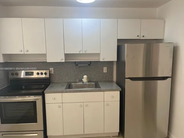 a kitchen with a refrigerator sink and cabinets