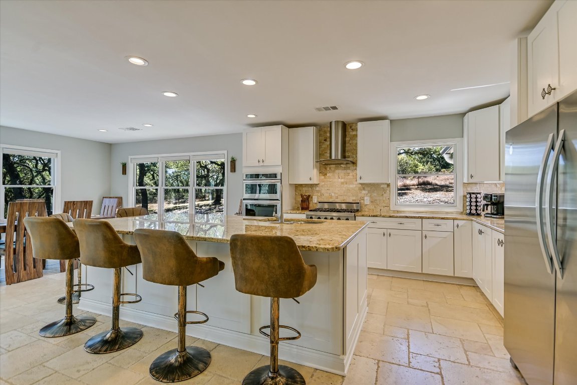 878 Ranch Road 2766 Johnson City, TX 78636 - Photo 10 of 40 a kitchen with stainless steel appliances kitchen island granite countertop a refrigerator a stove a dining table and chairs with wooden floor