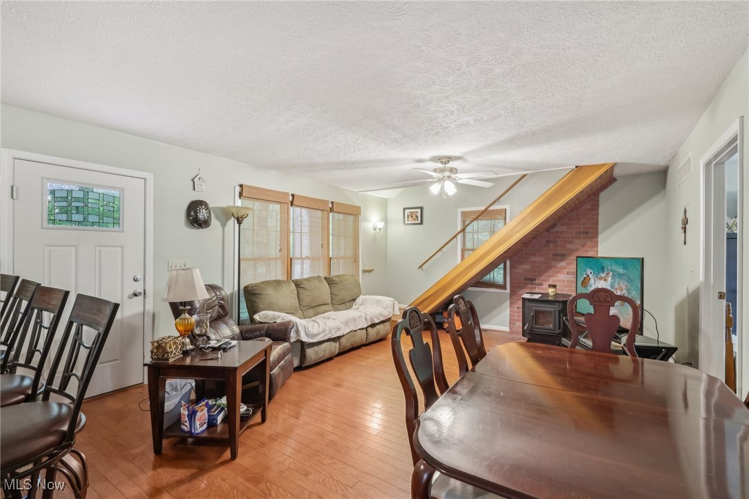 2490 Dodgeville Road Rome, OH 44085 - Photo 6 of 42 Dining space featuring a wood stove, light wood-type flooring, a textured ceiling, ceiling fan, and stairs