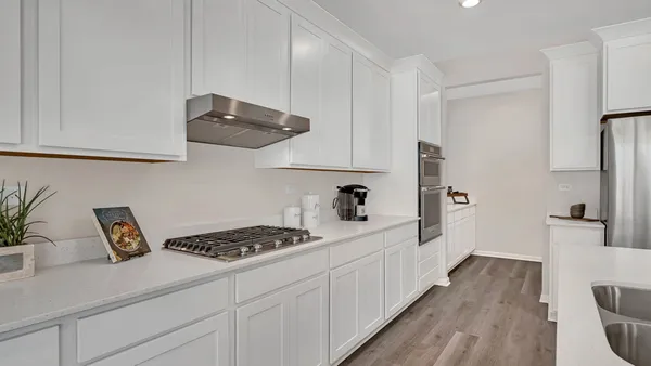 a kitchen with stainless steel appliances a sink a stove and white cabinets