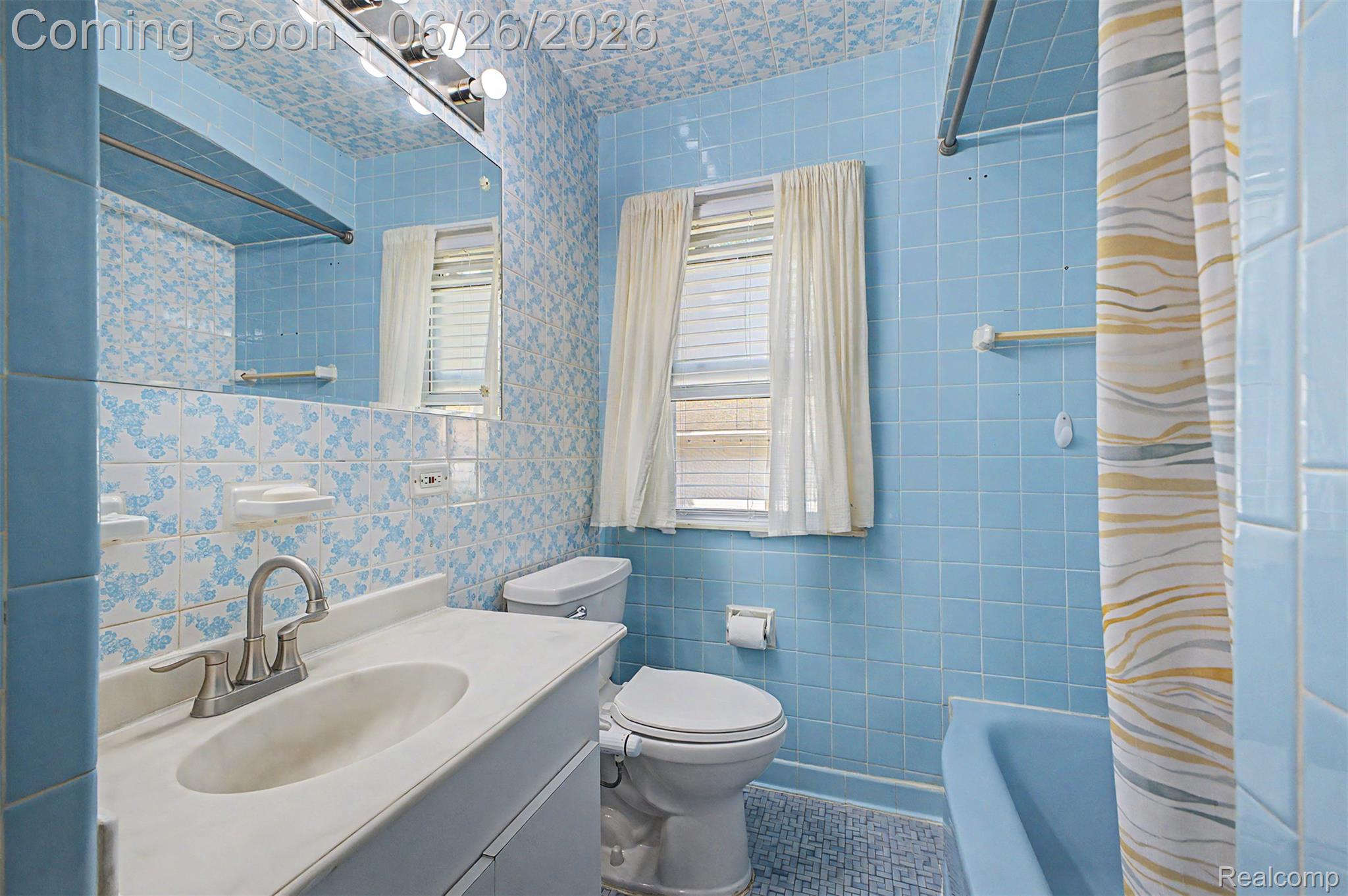 2216 Banner Street Dearborn, MI 48124 - Photo 12 of 34 Bathroom featuring a vanity with an integrated sink and brushed nickel faucet, a large wall-mounted mirror, a window with blinds, and blue tiled walls