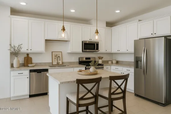a kitchen with stainless steel appliances a stove a sink a microwave a refrigerator and white cabinets
