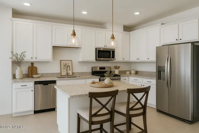 a kitchen with stainless steel appliances a stove a sink a microwave a refrigerator and white cabinets