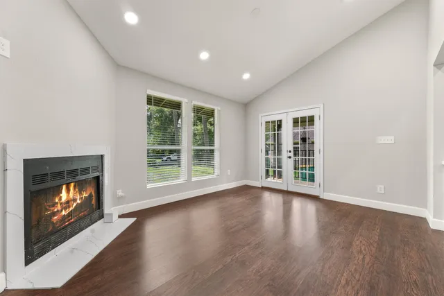 a view of an empty room with wooden floor fireplace and a window