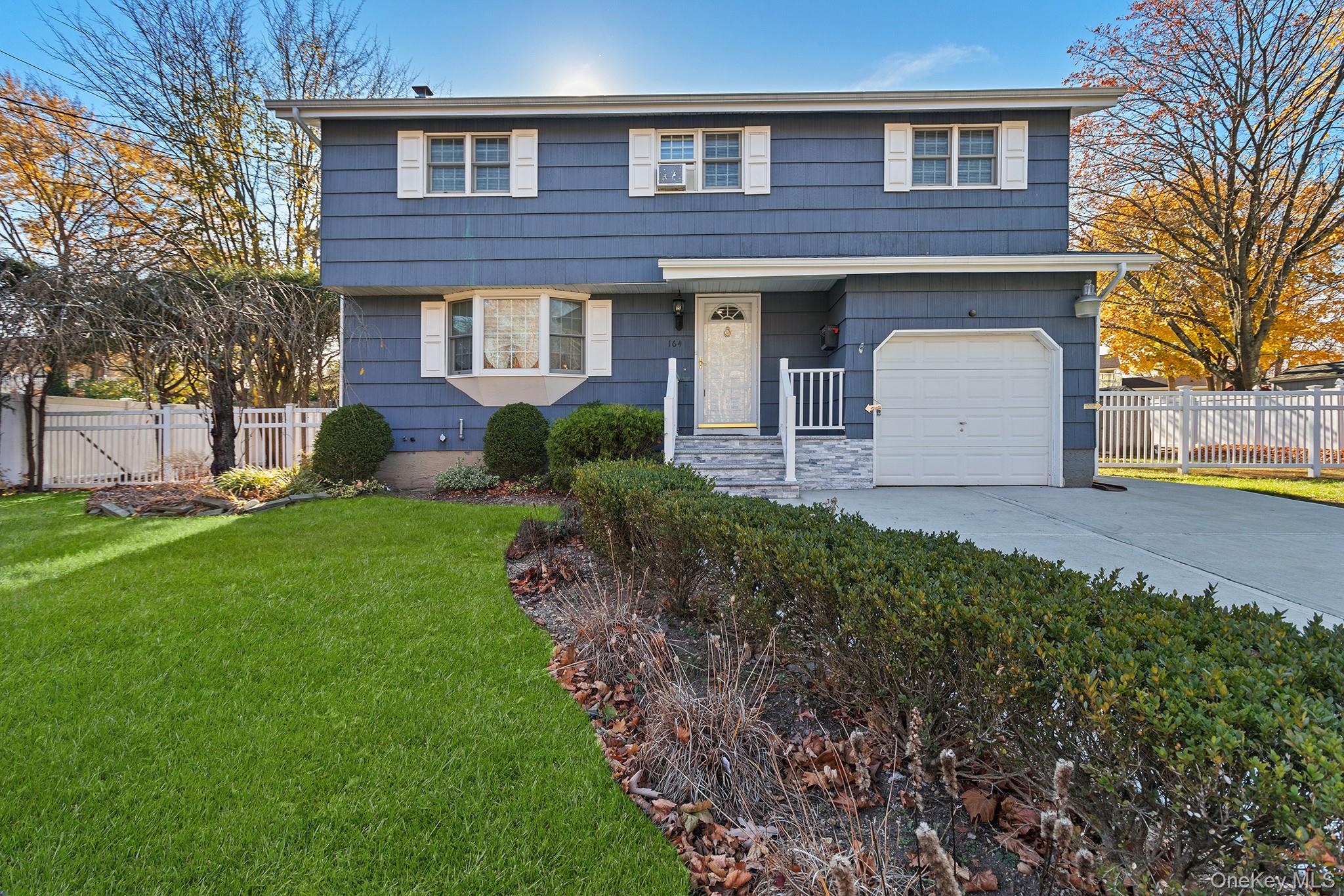 a front view of a house with garden and trees