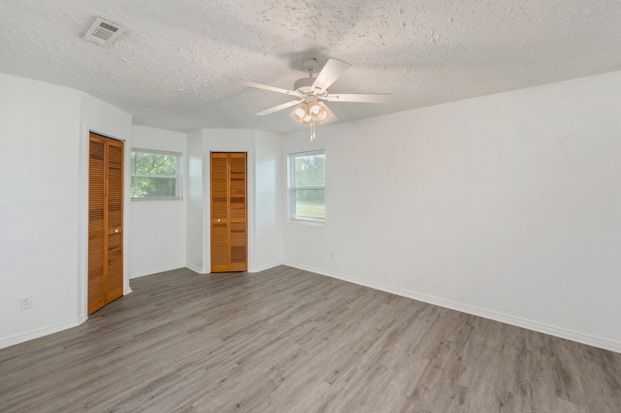 1099 Highway 2 Westville, FL 32464 - Photo 17 of 34 an empty room with wooden floor chandelier fan and windows