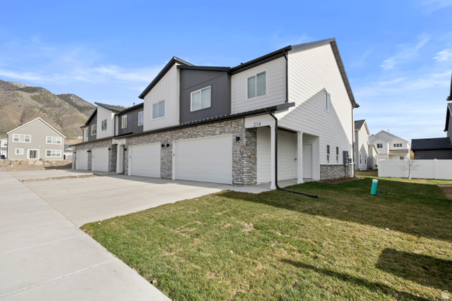 Contemporary townhome exterior featuring white siding, dark gray accents, and stone veneer detailing