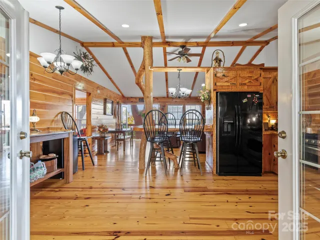 a kitchen with stainless steel appliances kitchen island granite countertop a stove a refrigerator a dining table and chairs with wooden floor