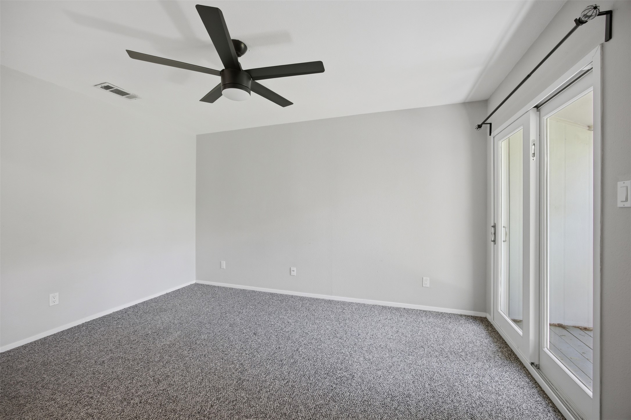 4204 Hudson Bend Road, Unit B Austin, TX 78734 - Photo 27 of 37 Spacious room featuring neutral grey carpeting, light grey walls, and a modern black ceiling fan