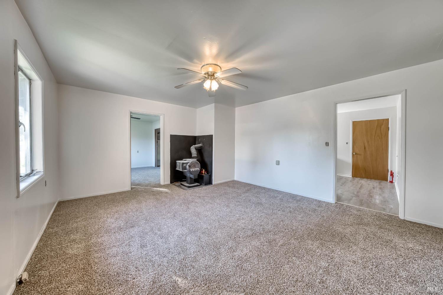 11415 Seigler Springs Road Middletown, CA 95461 - Photo 11 of 52 an empty room with a fireplace and a ceiling fan