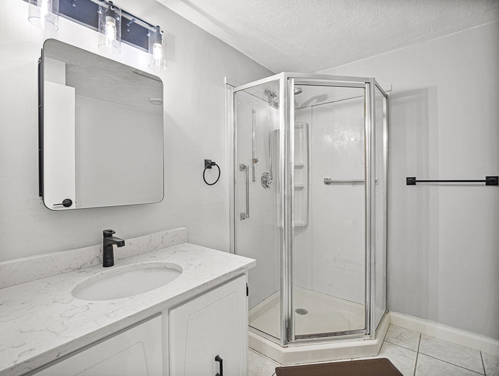 9 Broadway, Unit 110 Saugus, MA 01906 - Photo 13 of 27 a bathroom with a shower sink vanity and mirror