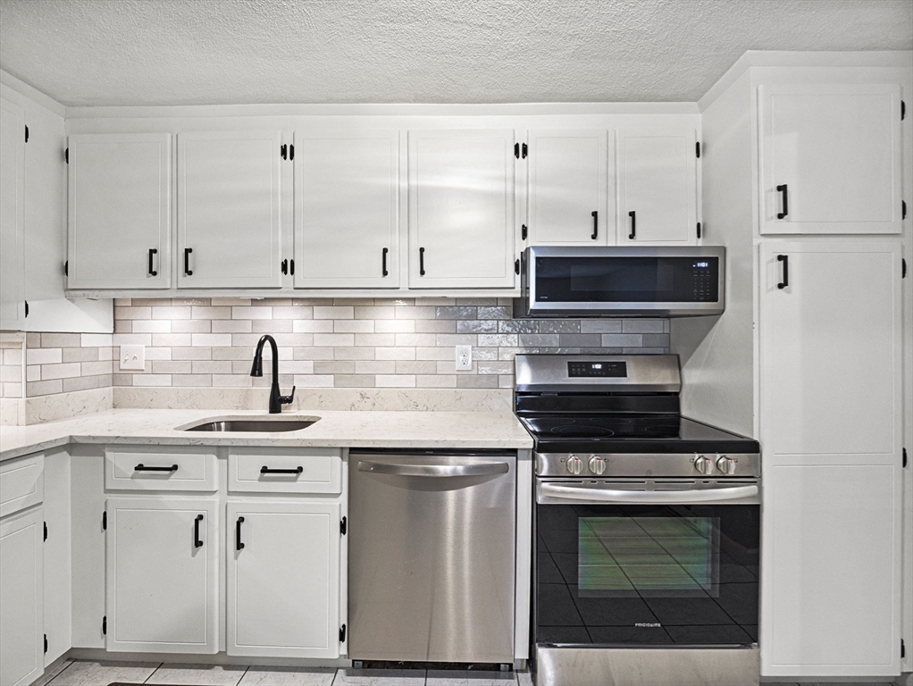 9 Broadway, Unit 110 Saugus, MA 01906 - Photo 6 of 27 a kitchen with granite countertop white cabinets and white appliances