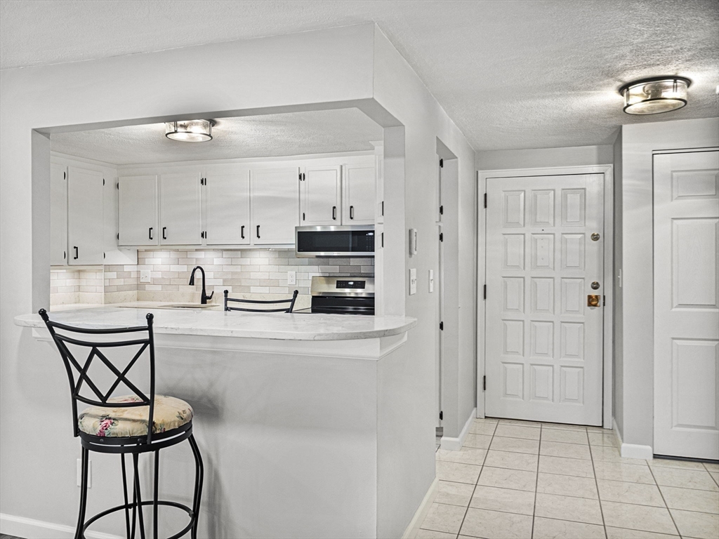 9 Broadway, Unit 110 Saugus, MA 01906 - Photo 9 of 27 a kitchen with stainless steel appliances a refrigerator a sink dishwasher and white cabinets