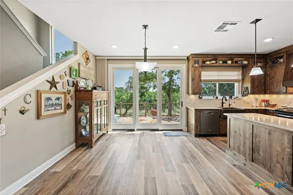 a view of a kitchen with kitchen island a counter top space a sink a wooden floor and a window