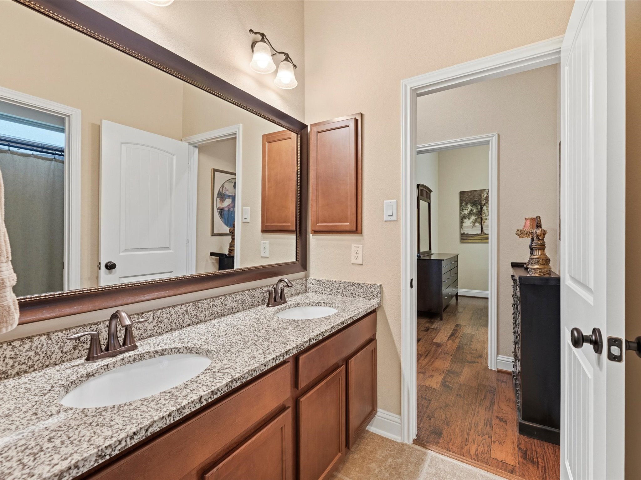 3907 Randle Ridge Court Fulshear, TX 77441 - Photo 23 of 46 This first-floor bathroom between front bedroom and study features a double vanity with granite countertops and modern fixtures. It connects to a bedroom and study with hardwood flooring and has a private water closet/shower area for multiple individual use.