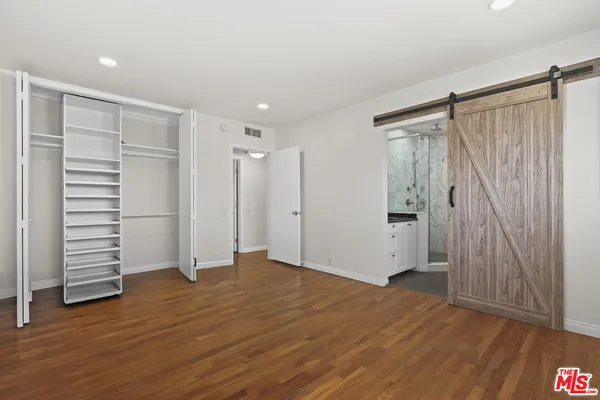 an empty room with wooden floor closet and windows