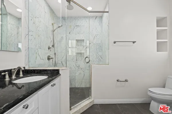 a bathroom with a granite countertop sink toilet and shower