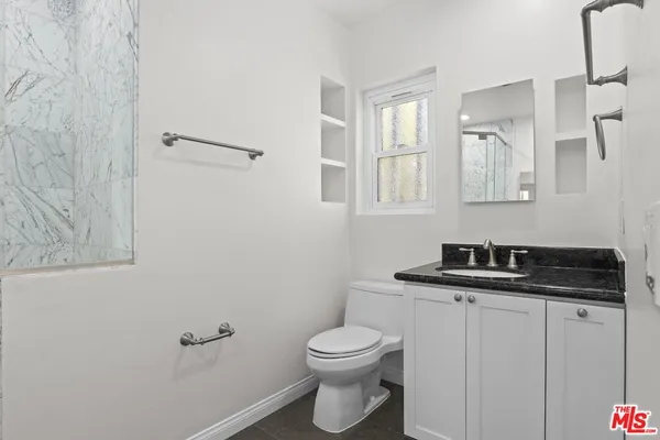a bathroom with a granite countertop toilet a sink and mirror