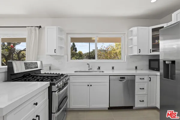a kitchen with white cabinets stainless steel appliances and sink