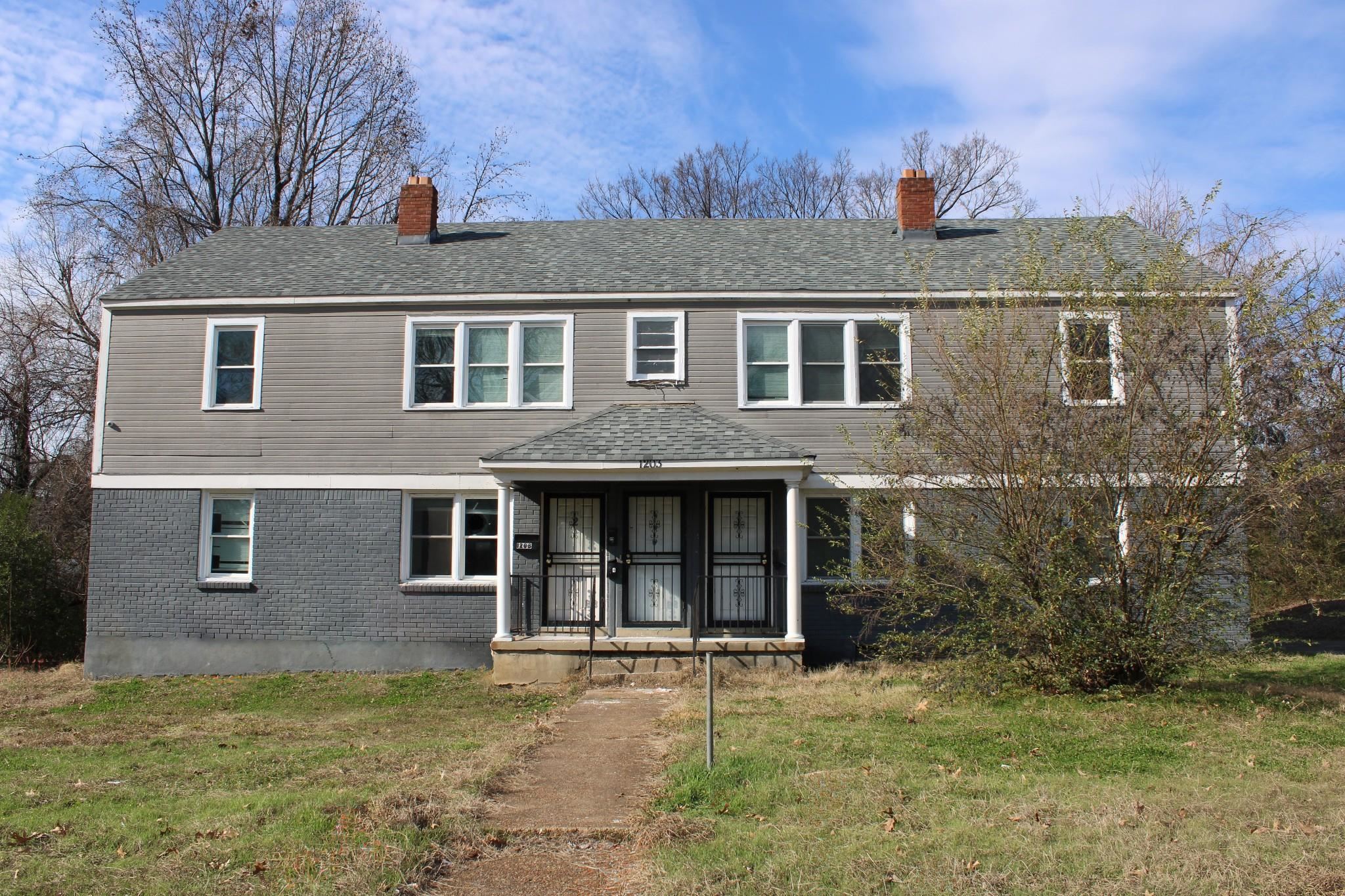 View of front of property featuring a front lawn, a chimney, brick siding, and a shingled roof