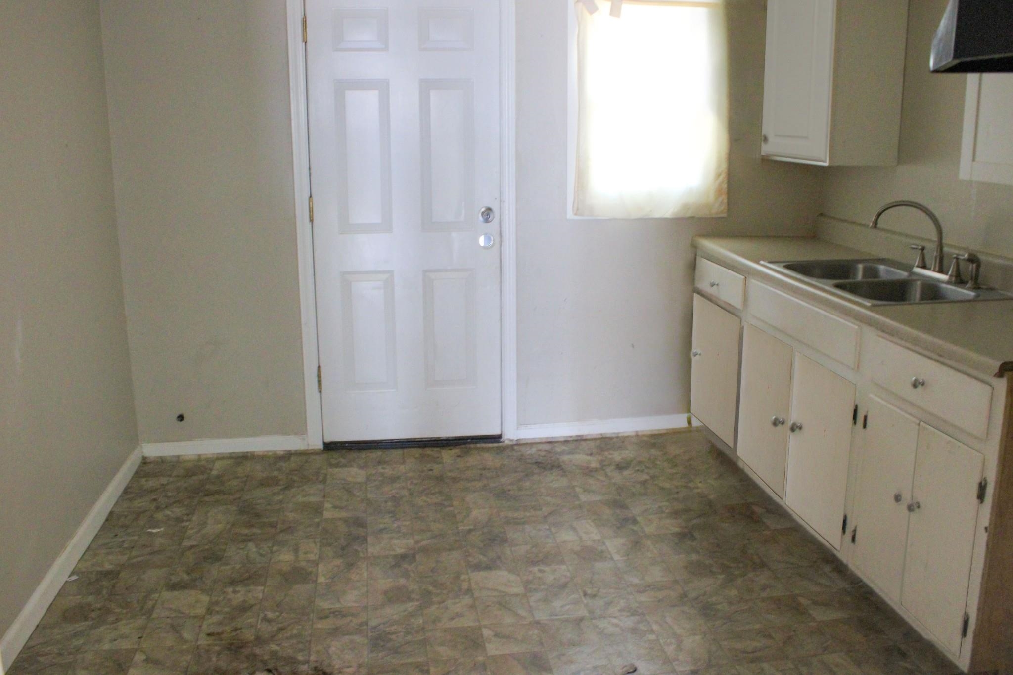 1203 Aubra Road Memphis, TN 38111 - Photo 7 of 10 Kitchen with light countertops, white cabinetry, stone finish flooring, and exhaust hood