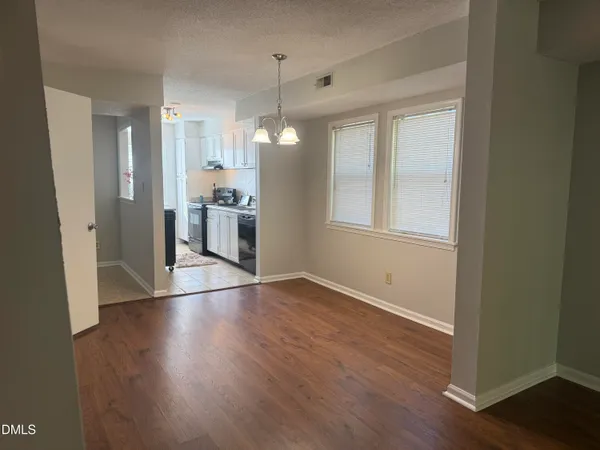 a view of an empty room with window and wooden floor