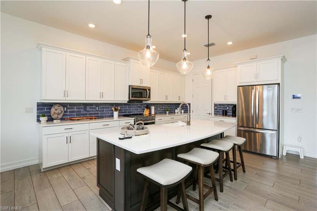 14656 Kelson Circle Naples, FL 34114 - Photo 34 of 50 a kitchen with stainless steel appliances kitchen island granite countertop a sink a stove a refrigerator and white cabinets with wooden floor