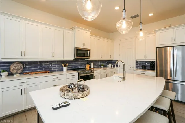 a kitchen with stainless steel appliances a stove a sink a microwave a refrigerator and cabinets