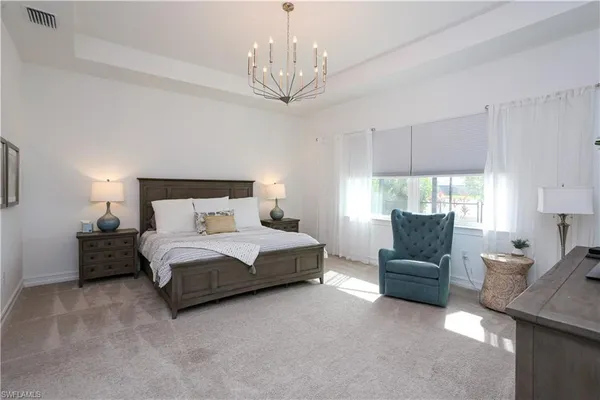 a spacious bedroom with a bed and a chandelier