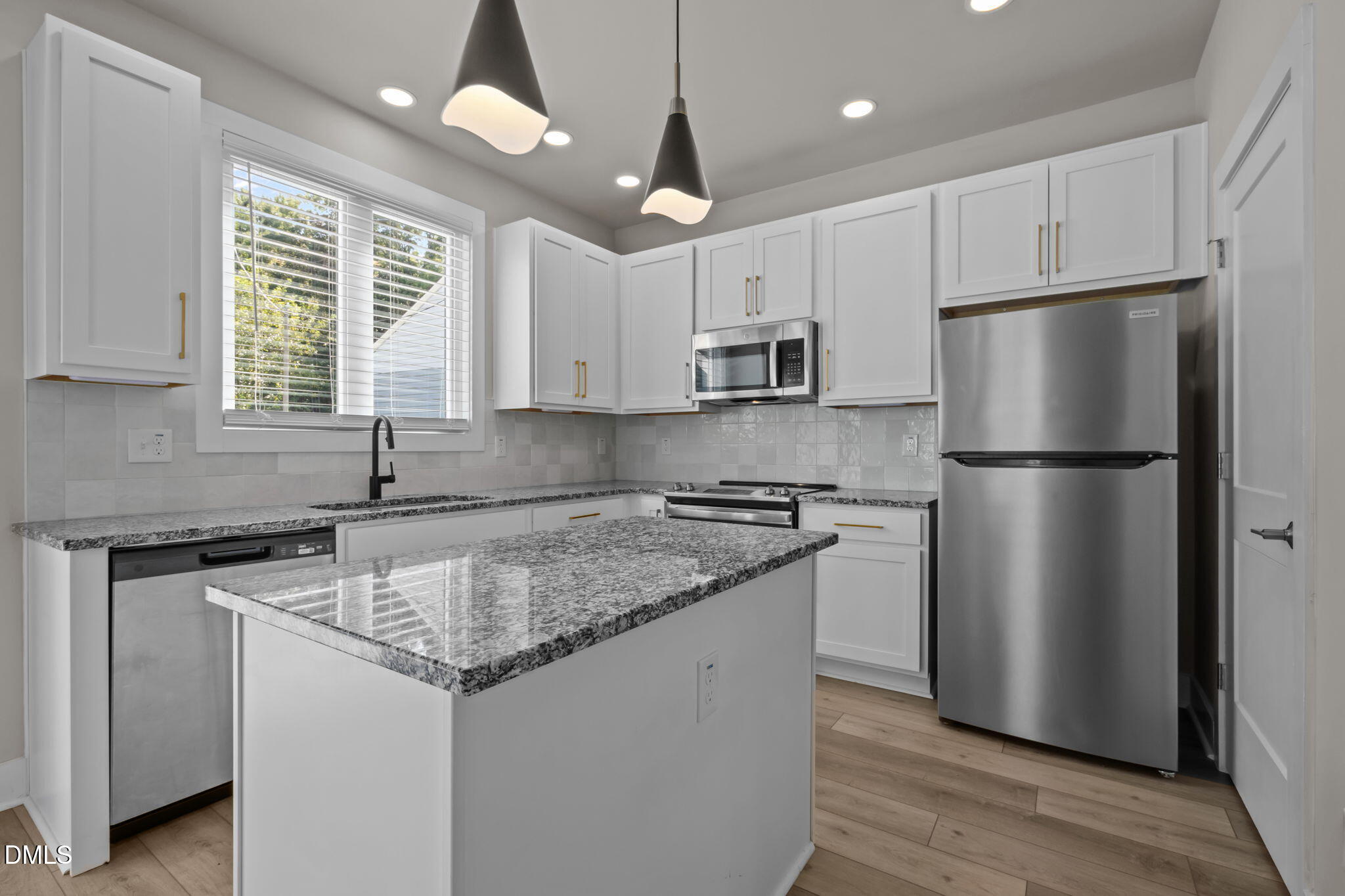 421 Eugene Street, Unit A Durham, NC 27701 - Photo 15 of 38 a kitchen with stainless steel appliances granite countertop a refrigerator a sink dishwasher a kitchen island with wooden floor and cabinets
