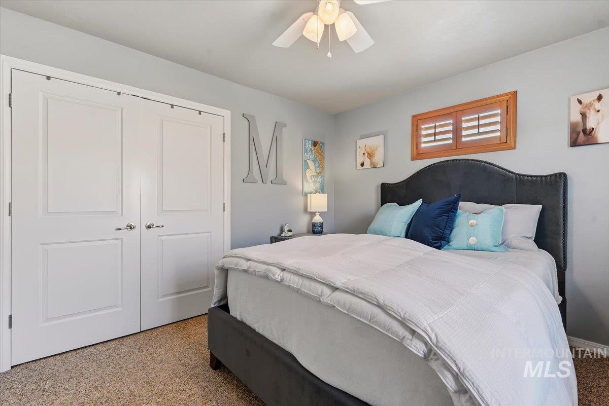 11660 Timber Butte Road Sweet, ID 83670 - Photo 24 of 49 Light gray wall paint, textured carpet, white double closet doors, a ceiling fan, and a wood-frame window with louvers