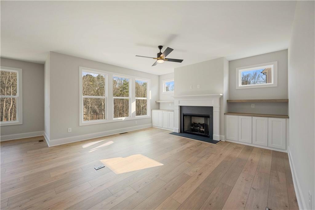 126 Spaulding Lane Woodstock, GA 30188 - Photo 7 of 48 an empty room with windows a fireplace and wooden floor