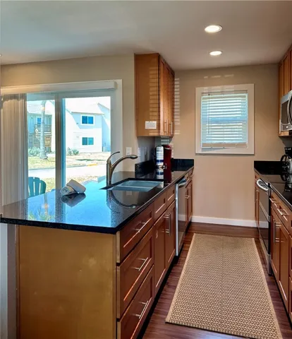 a kitchen with granite countertop a sink a counter top space and stainless steel appliances