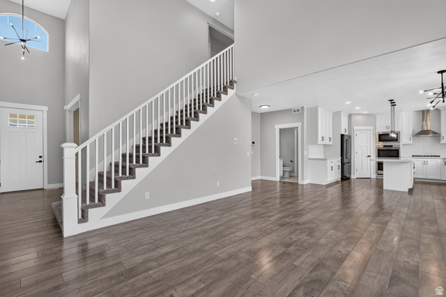 36 West Syracuse Road Vineyard, UT 84059 - Photo 10 of 56 Open-concept living area featuring wood-finish flooring, a contemporary white kitchen with black appliances, a central island, and a built-in oven and microwave